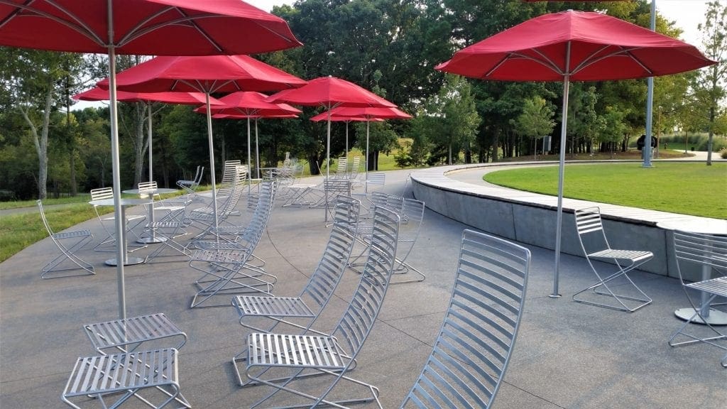 Iconic red umbrellas and modern aluminum furniture provide seating in the Ellipse.