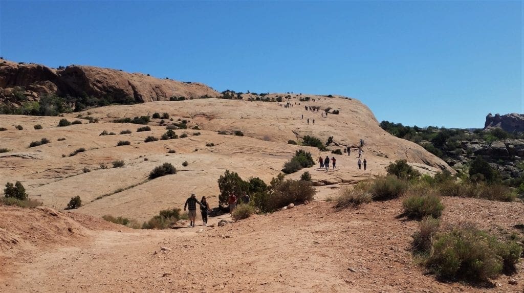 Hikers on slickrock slope in Utah, are all hiking together - but not too much.
