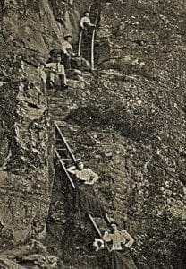 Gibson Girls climb ladders to the Pilot Mountain summit ~1900