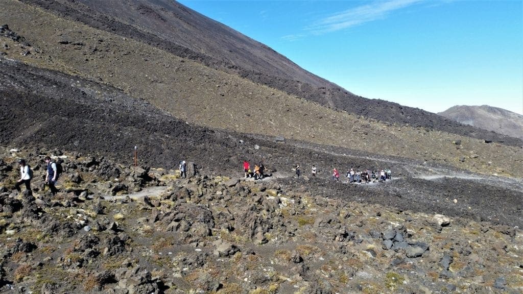 Hikers cross uneven lava-rock field in New Zealand